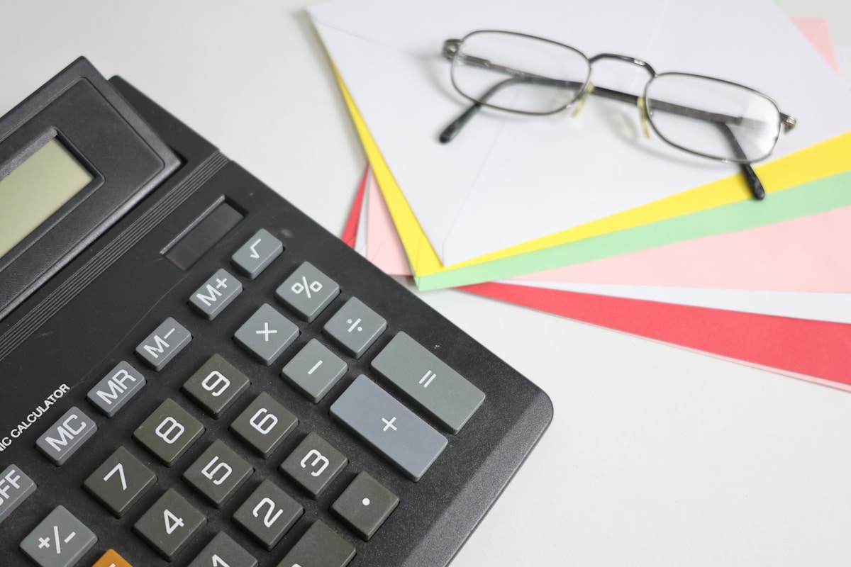 Calculatrice, lunettes, papiers colorés, outils de bureau.