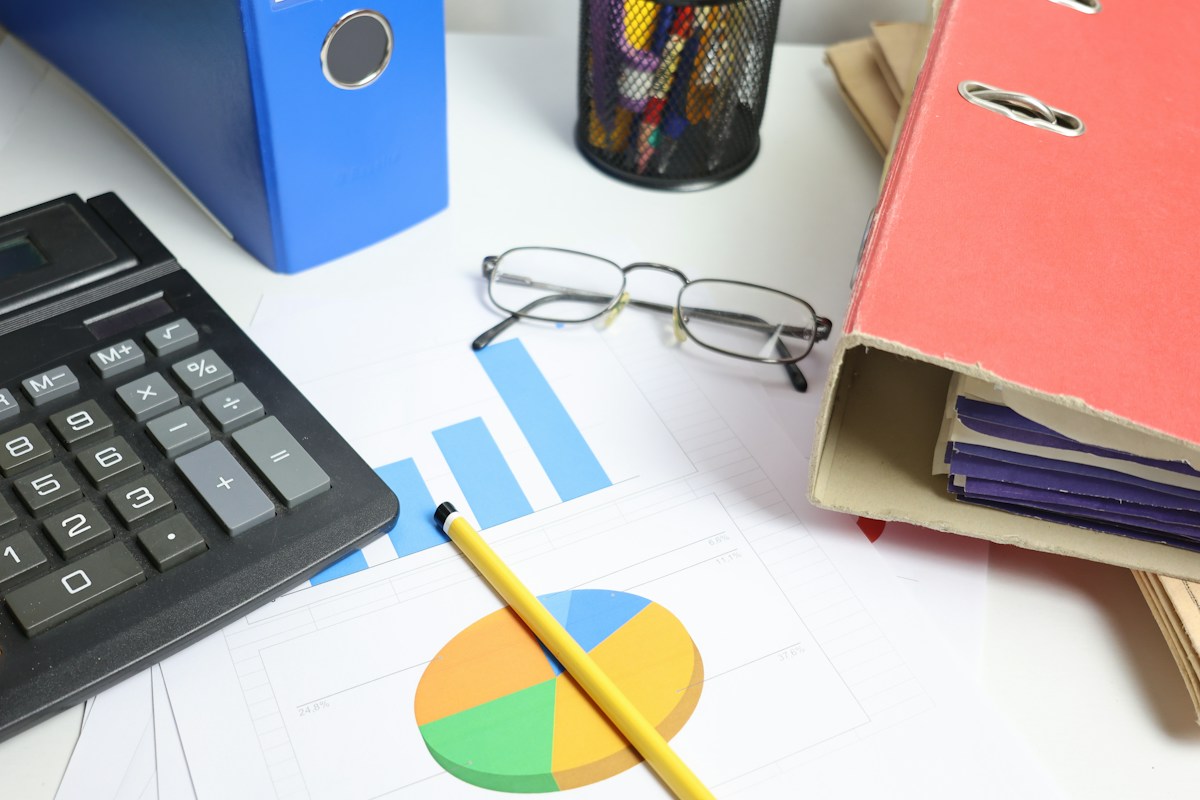 Bureau avec calculatrice, lunettes, graphiques, crayon et classeurs colorés