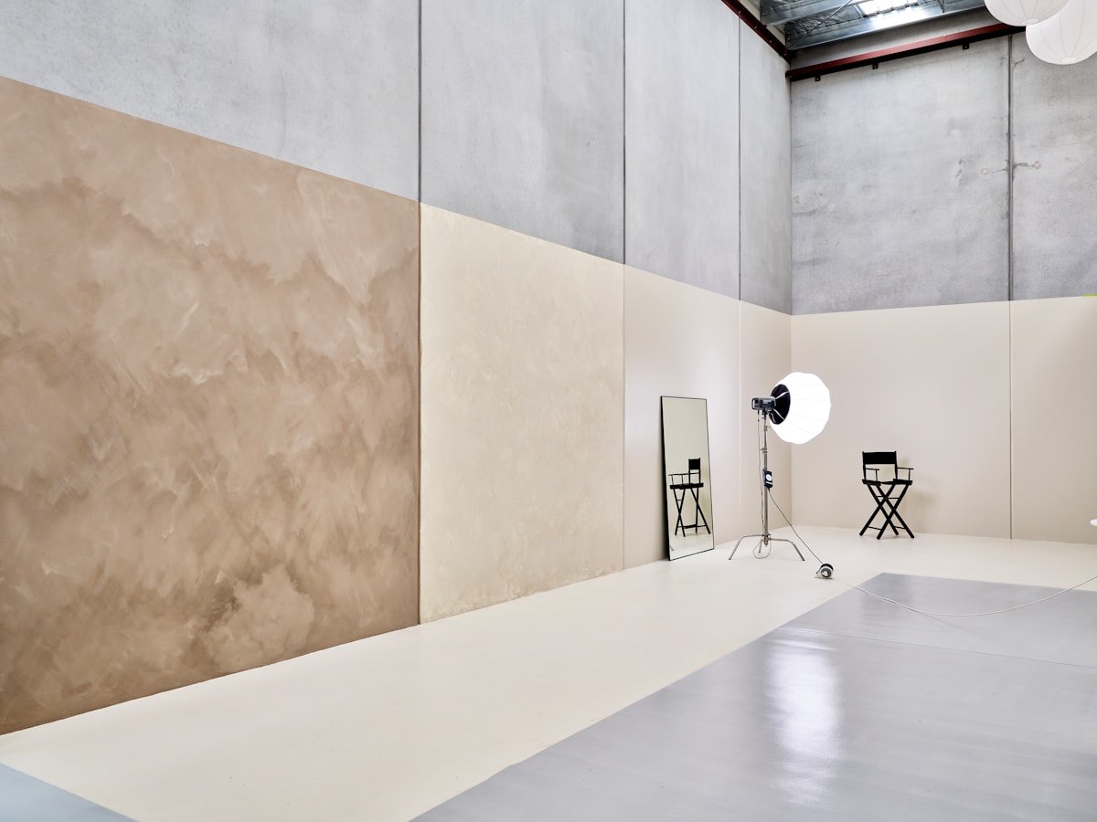 Salle de studio vide avec murs en béton et éclairage.