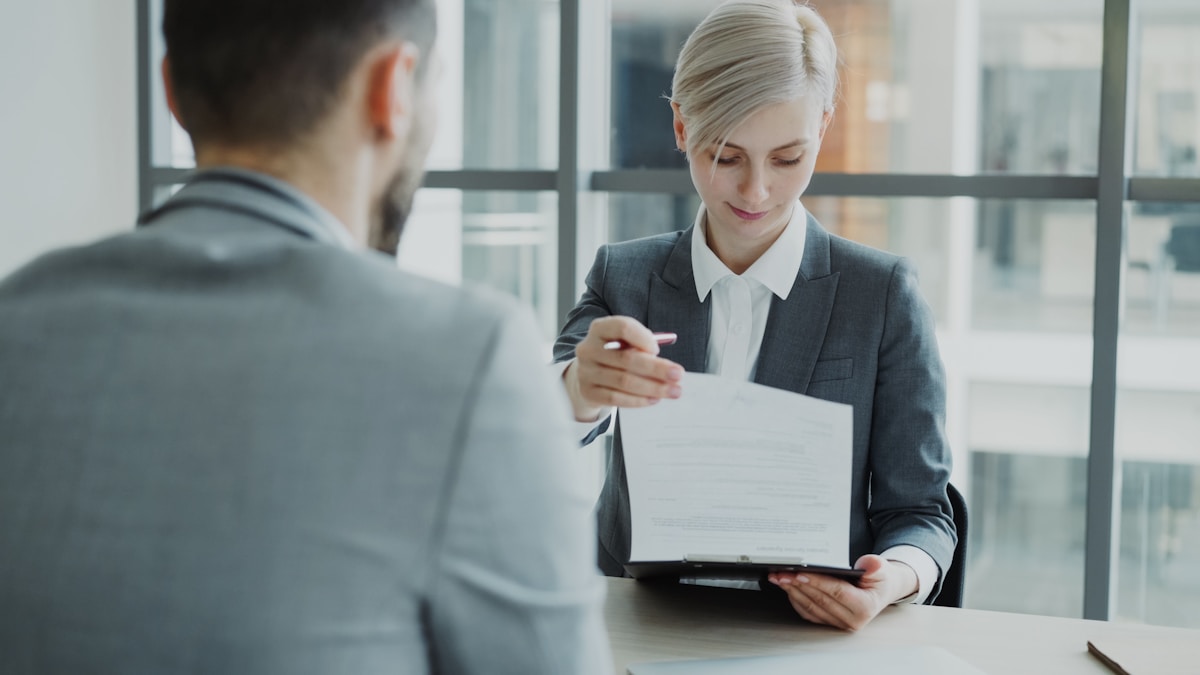 Deux professionnels en costume discutent d'un document dans un bureau.