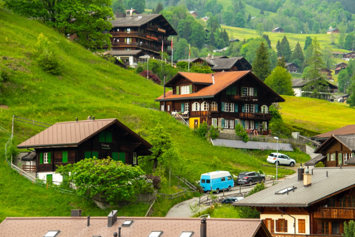 Paysage de village alpin avec maisons traditionnelles et voitures.