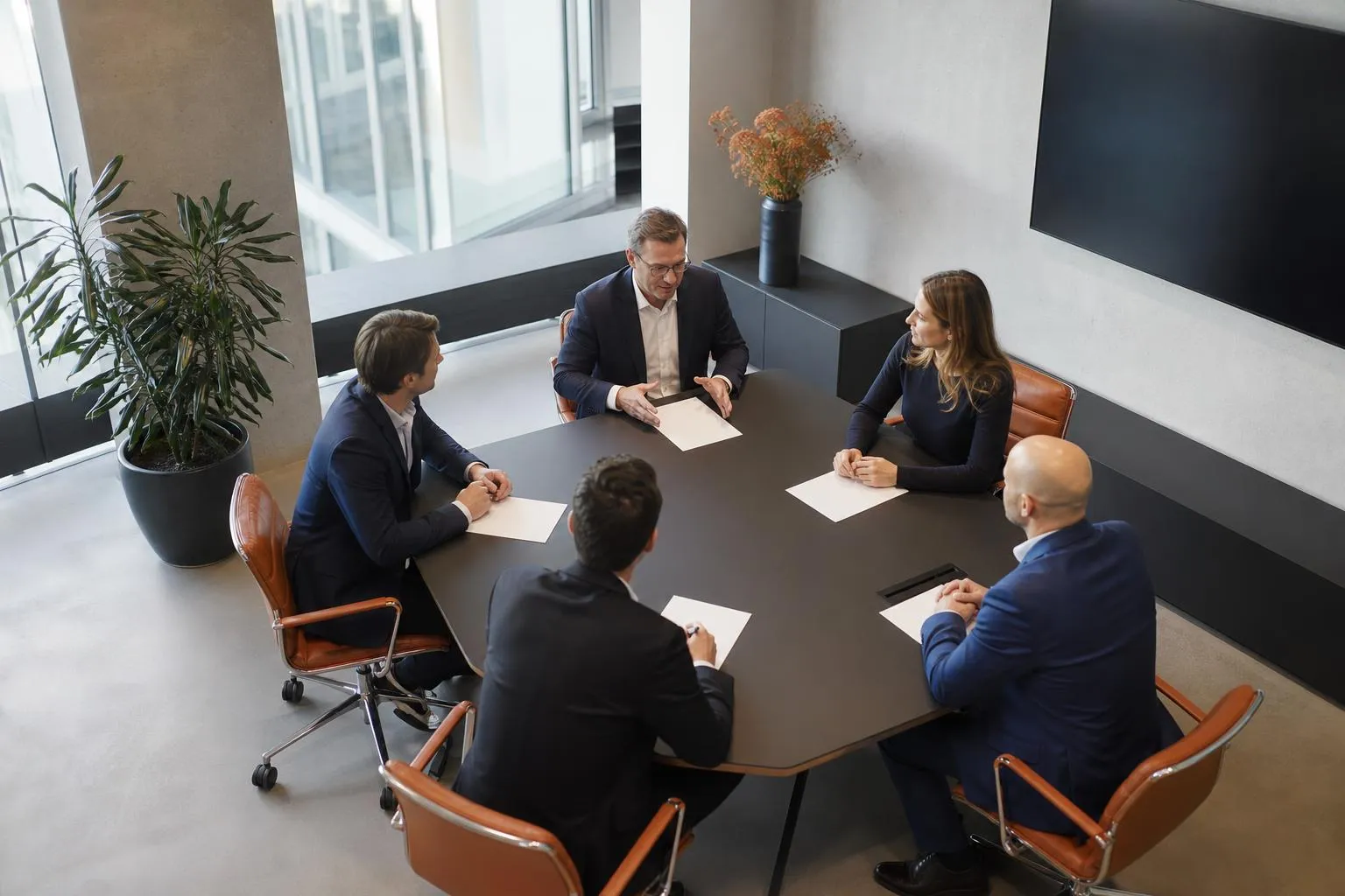 Réunion d’affaires de cinq professionnels autour d’une table.