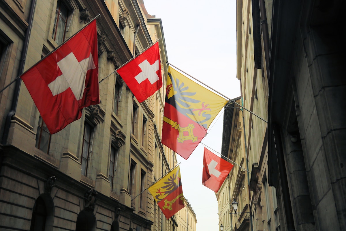 Drapeaux suisses et cantonaux suspendus dans une rue étroite.