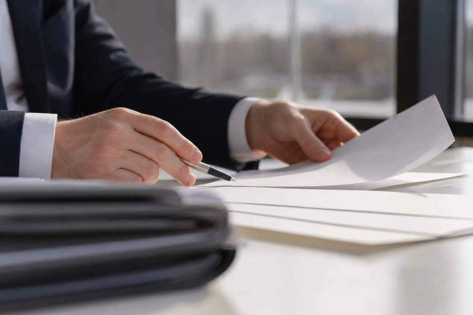 Mains d'un homme d'affaires signant des documents sur un bureau.
