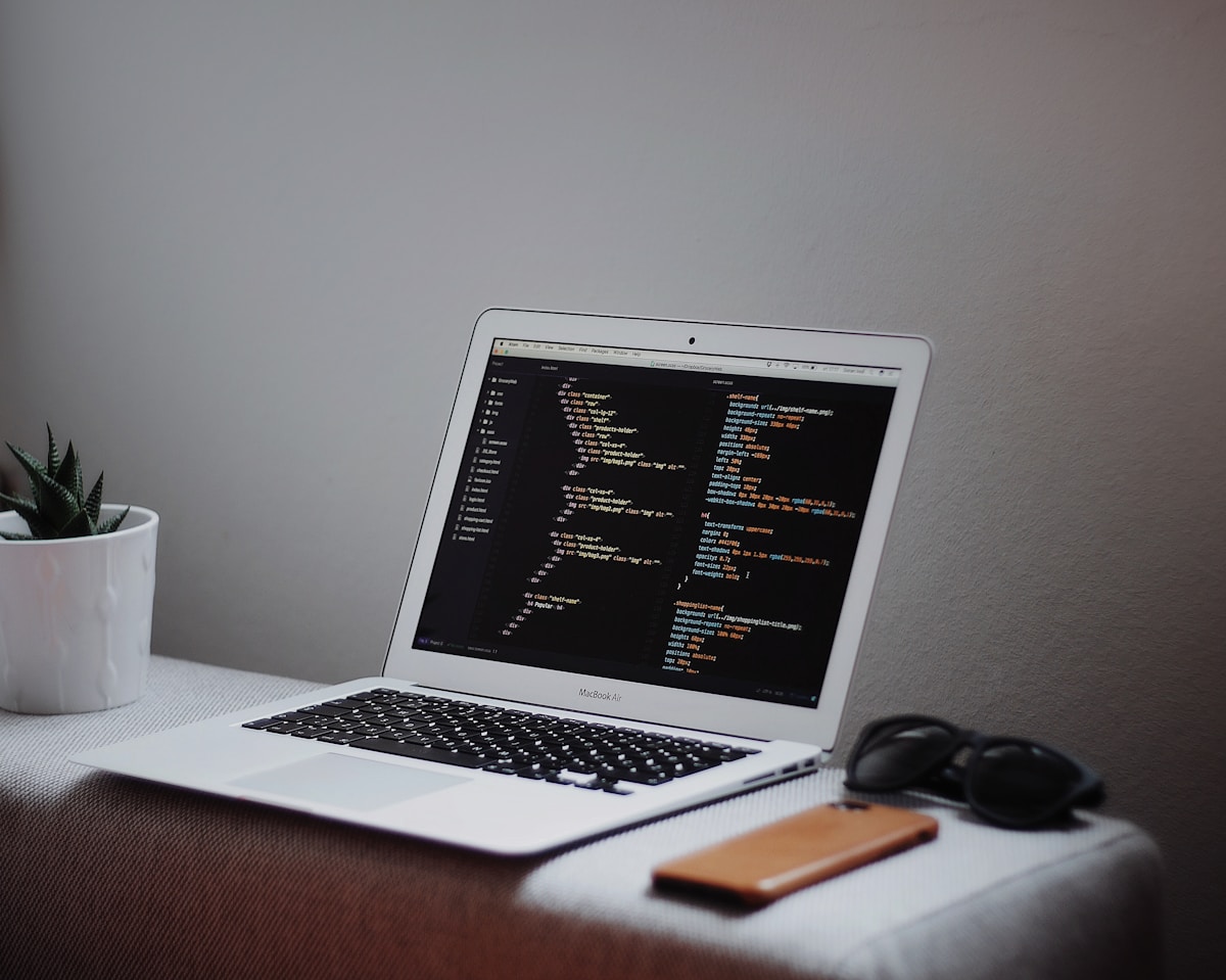 Ordinateur portable ouvert avec du code de programmation à l'écran, entouré d'accessoires de bureau.
