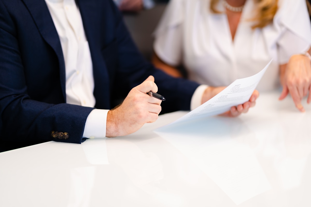 Deux personnes en costume signant un document officiel.