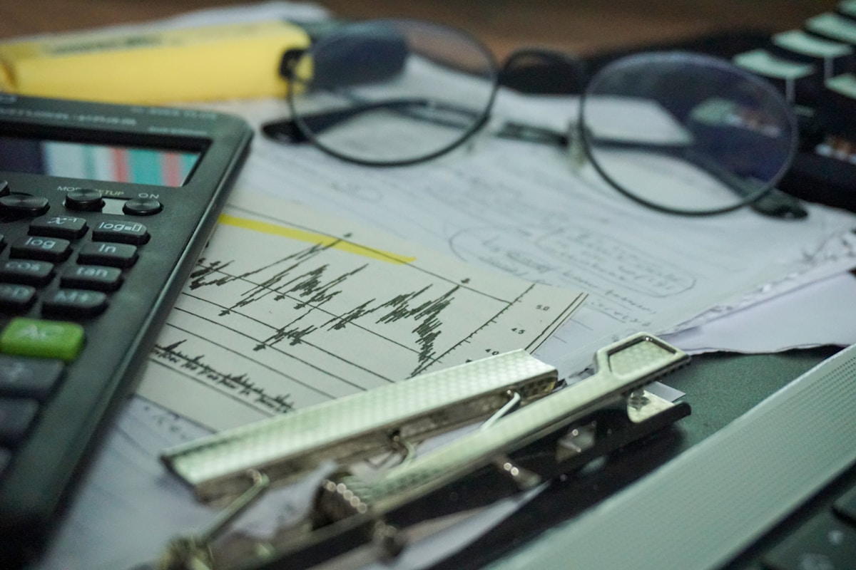 Graphique financier avec calculatrice, lunettes et stylo.