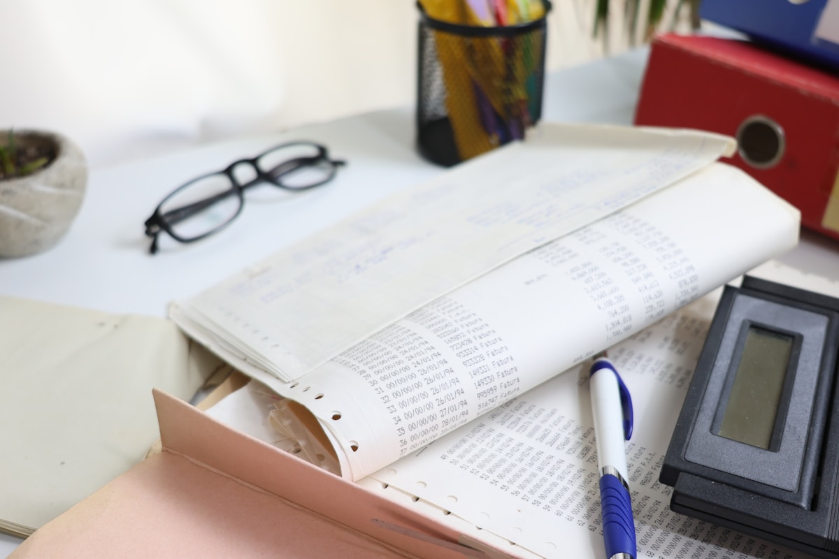 Bureau de travail avec documents, calculatrice et lunettes.