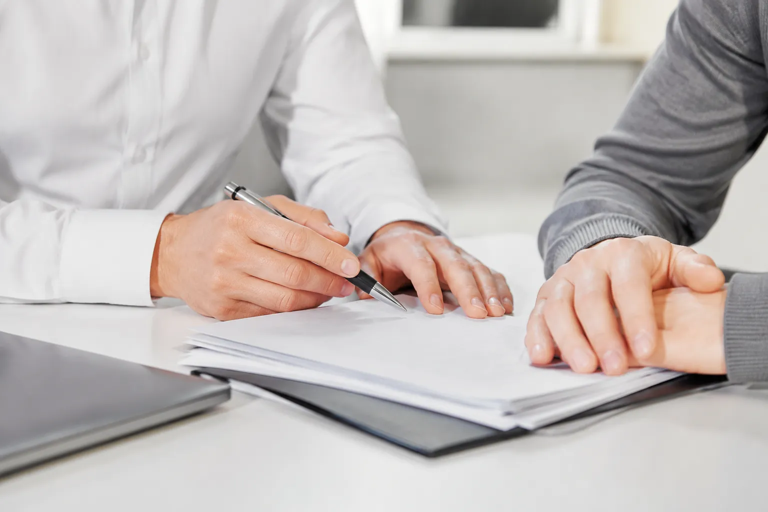 Mains d'un homme d'affaires signant des documents sur un bureau.
