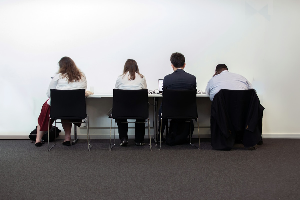 Groupe de personnes assises à des bureaux, travaillant sur des ordinateurs.