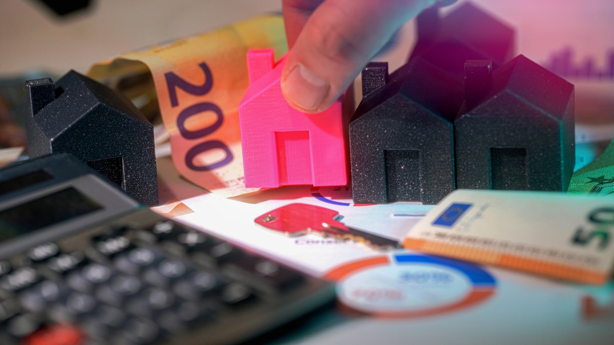Modèles de maison, calculatrice, billets de banque et documents financiers.