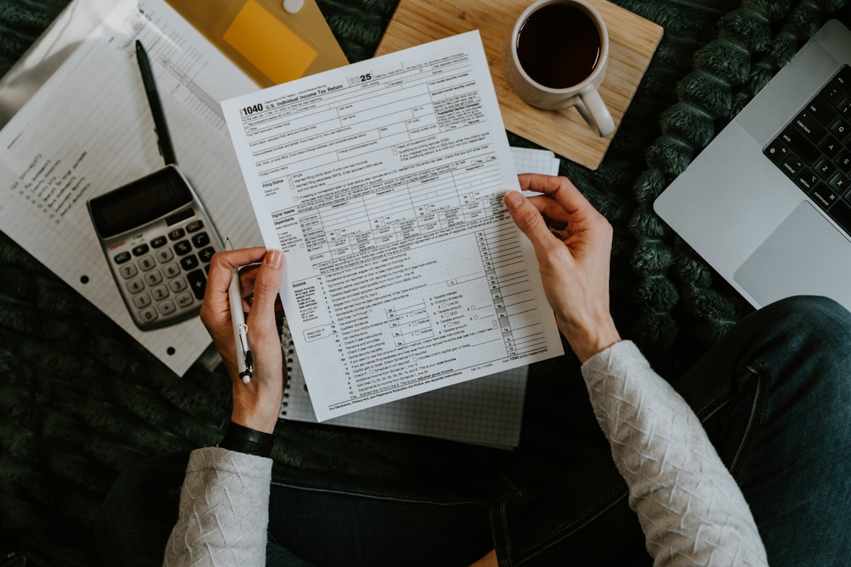 Formulaire fiscal 1040 sur un bureau avec ordinateur portable et tasse de café.