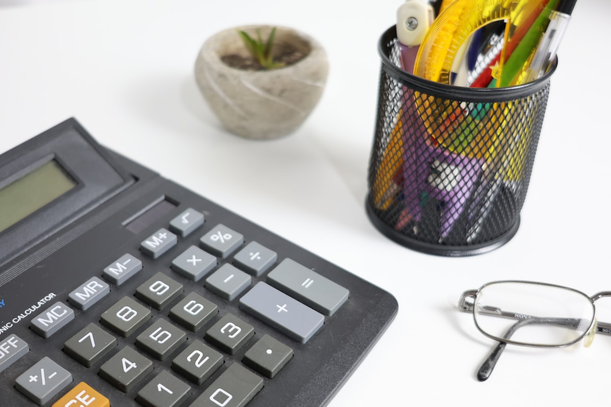 Bureau de travail avec calculatrice, plante et fournitures de bureau.