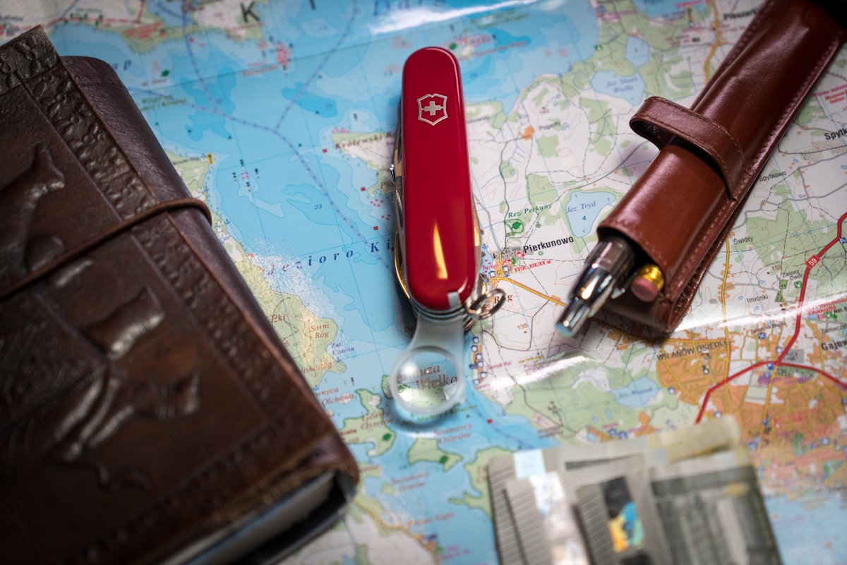 Cartes géographiques, couteau suisse rouge, carnets de voyage, accessoires de randonnée.