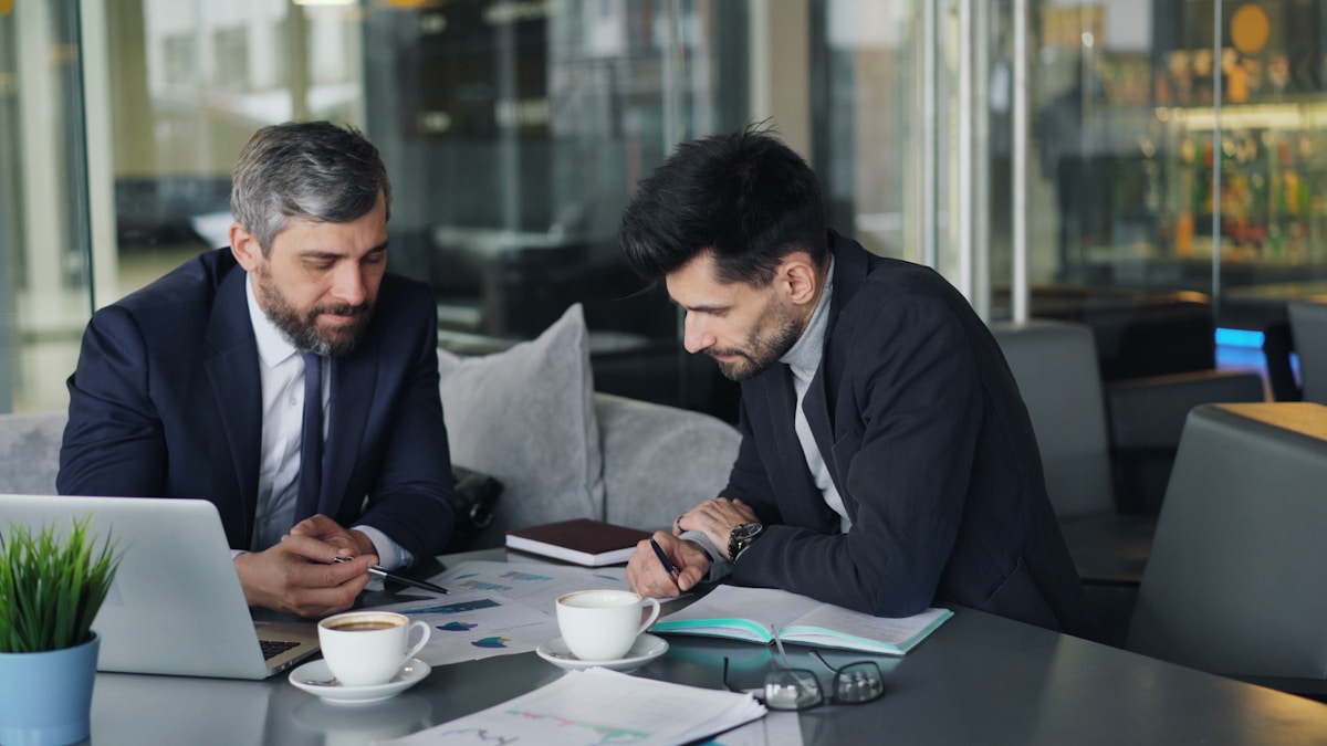 Deux hommes d'affaires en costume travaillant ensemble sur un ordinateur portable.