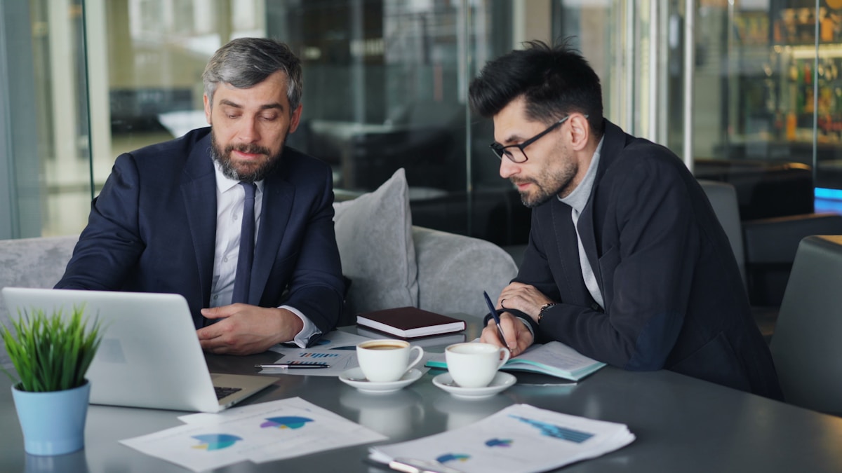 Deux hommes d'affaires en costume travaillant ensemble sur un ordinateur portable.