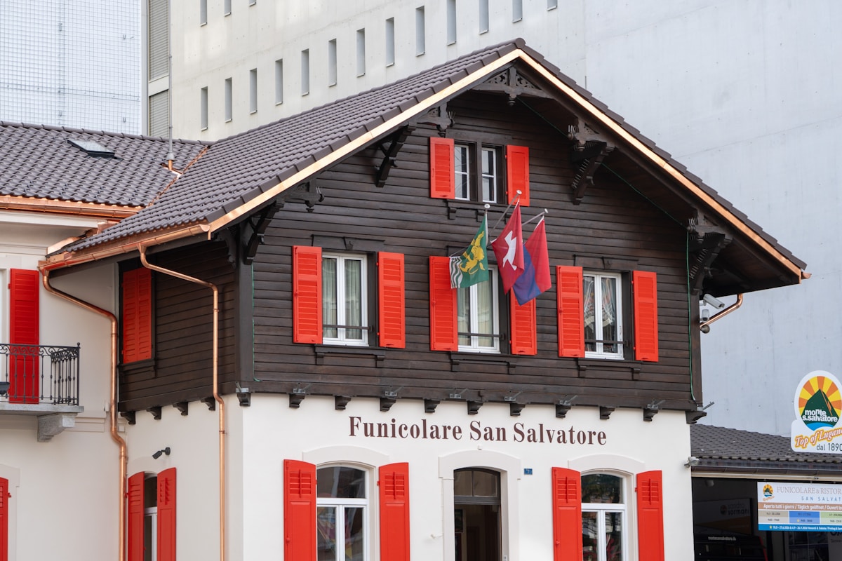 Bâtiment en bois avec volets rouges et drapeaux suisses.