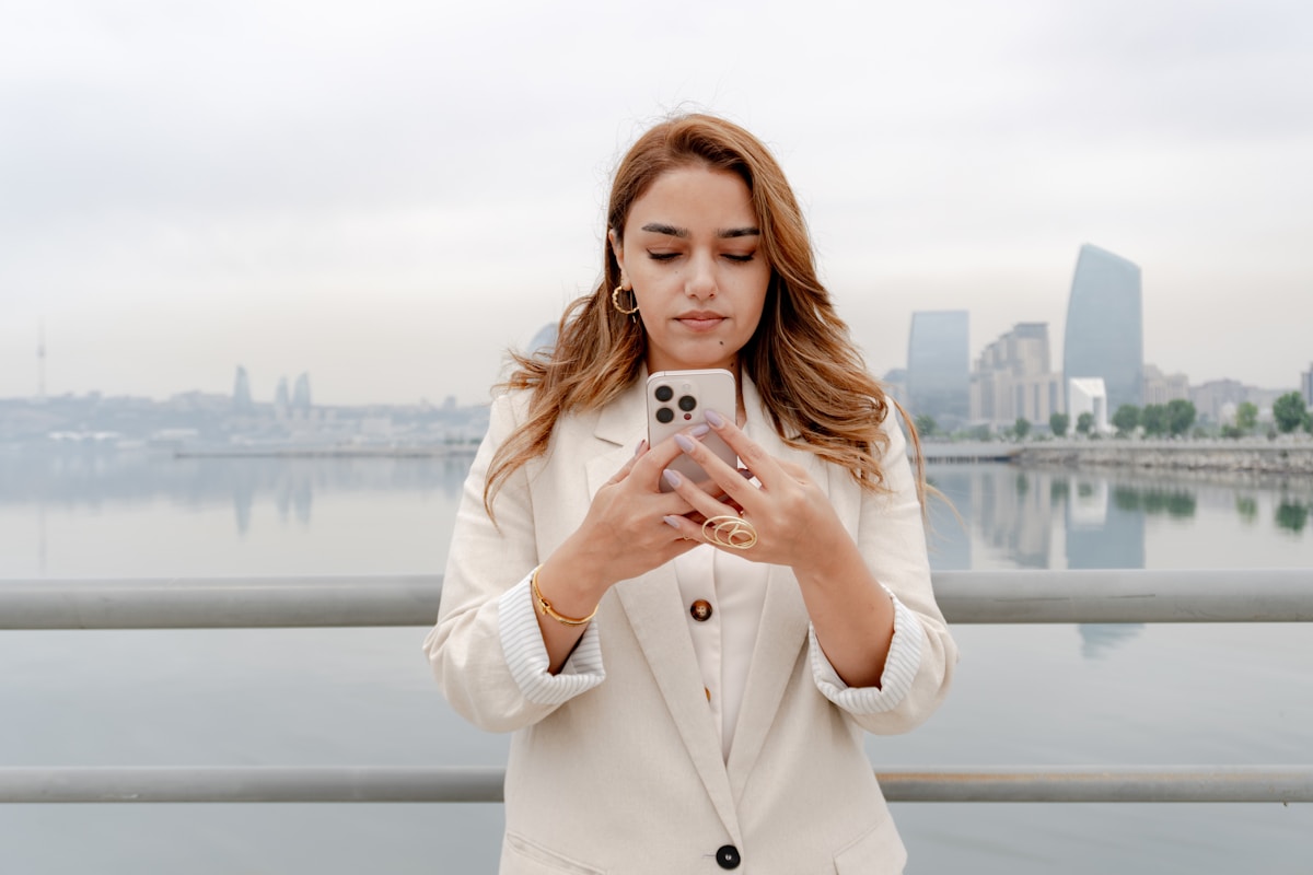 Woman s at her phone with a city backdrop.