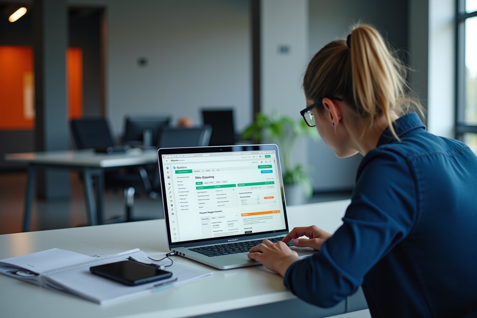 A person working on a laptop in an office setting.