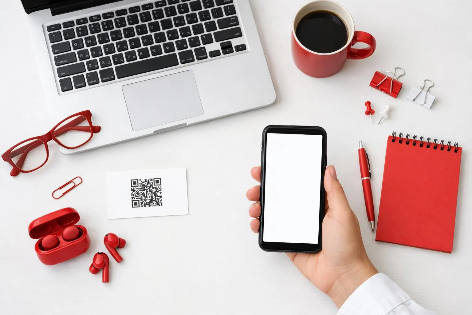 Laptop, smartphone, coffee mug, office supplies in red and white.