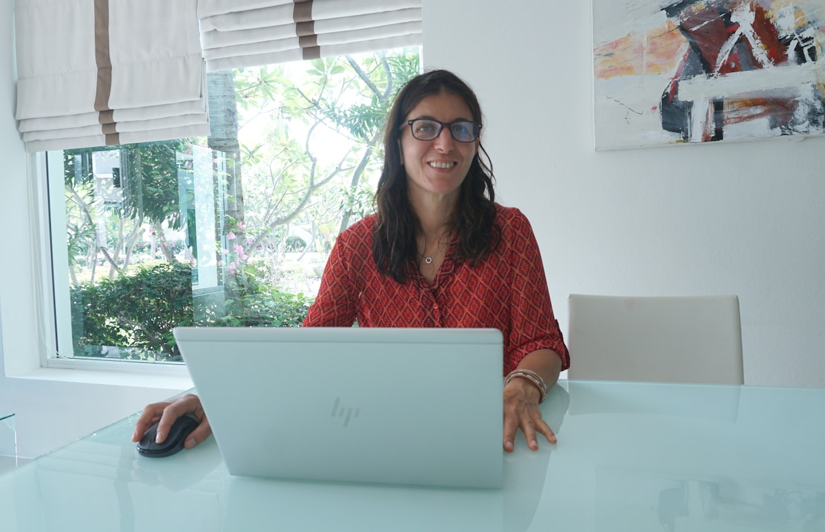 Woman works on laptop at a bright, modern table.