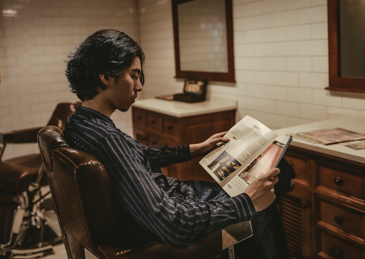 boy reading book while sitting on sofa chair