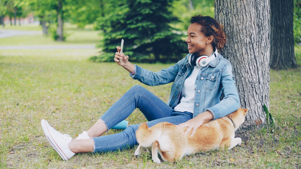 Woman takes a selfie with her dog in a park.