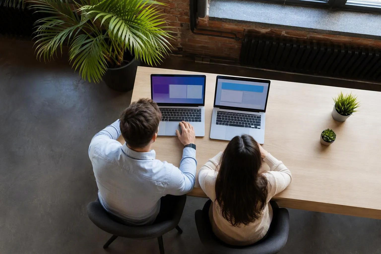 Two people working together on laptops in a cozy office setting.