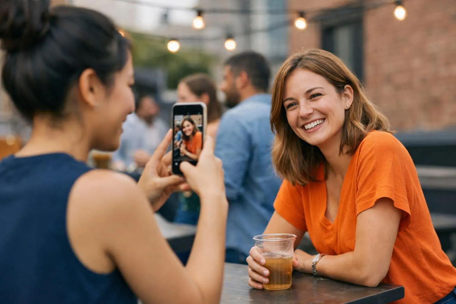 Two women taking a selfie, one smiling and holding a drink.