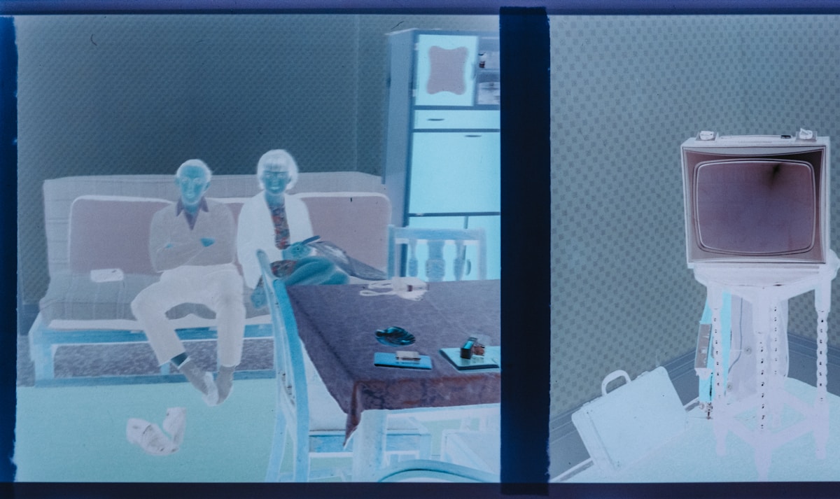 Two people sit on a couch in a room.