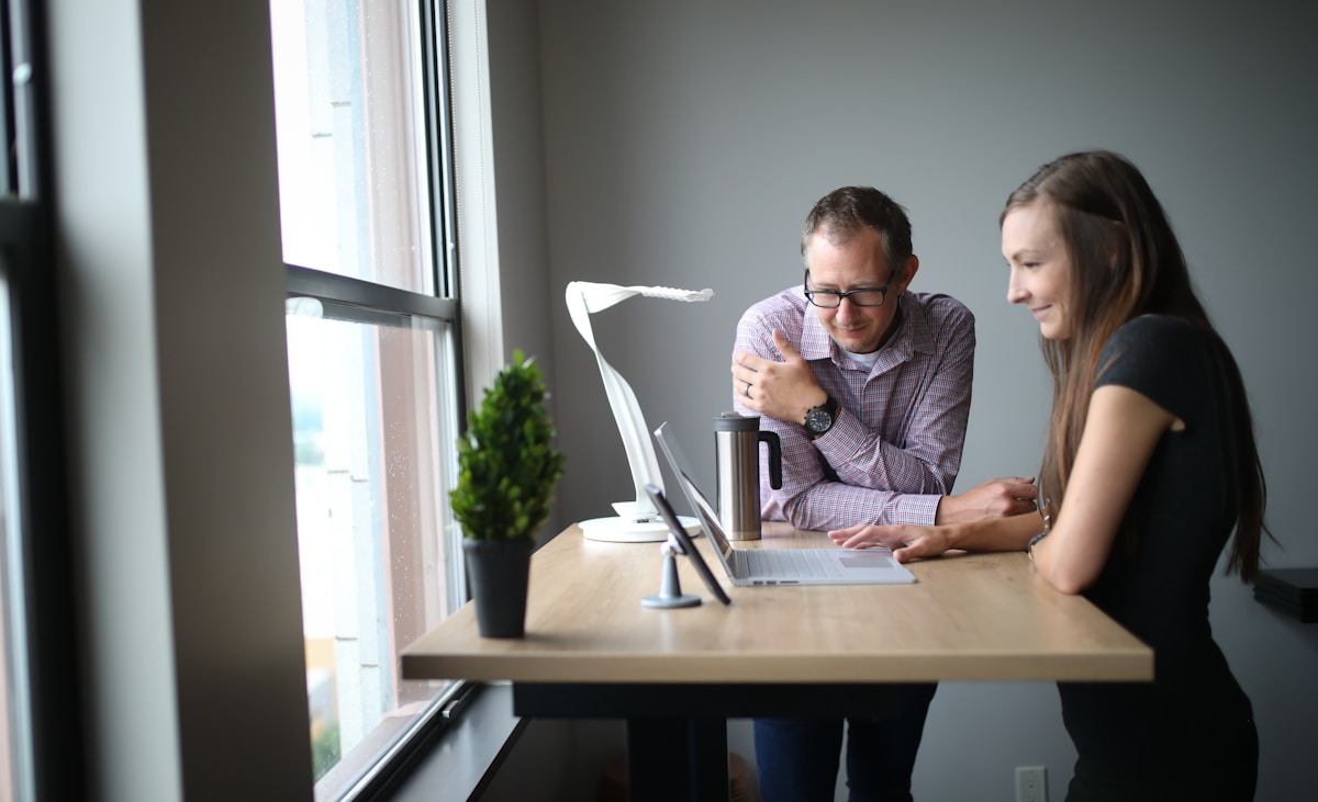 man in gray dress shirt using macbook air on brown wooden table