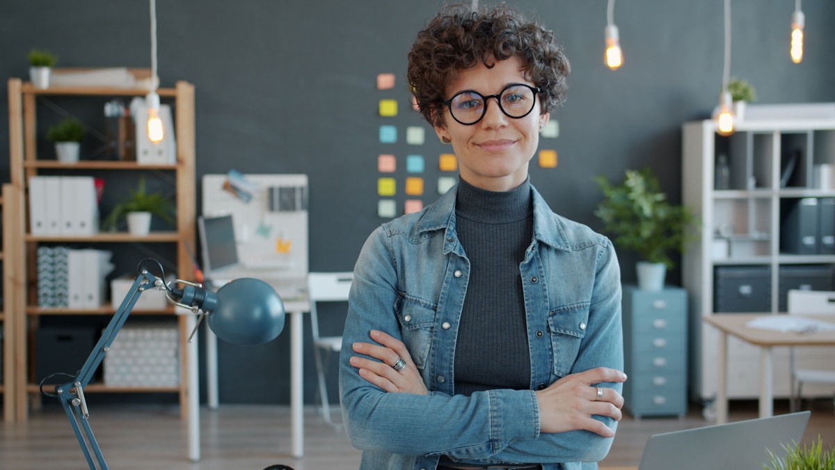 A woman with glasses smiles in an office