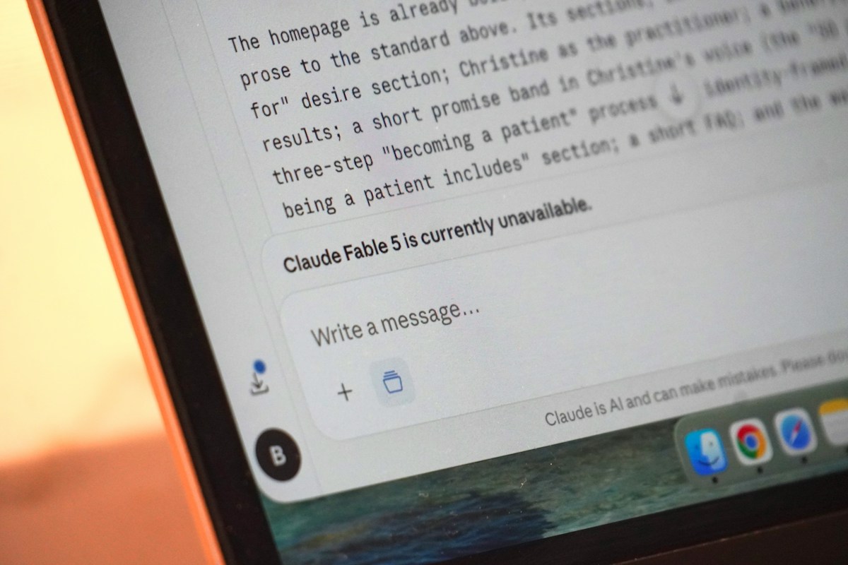 A laptop screen displays "claude fable 5 is currently unavailable."