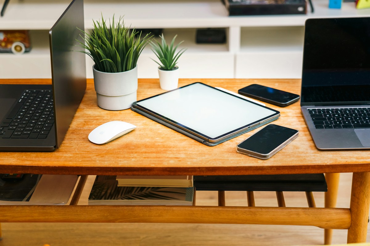 Devices like laptops, tablets, and phones are on a desk