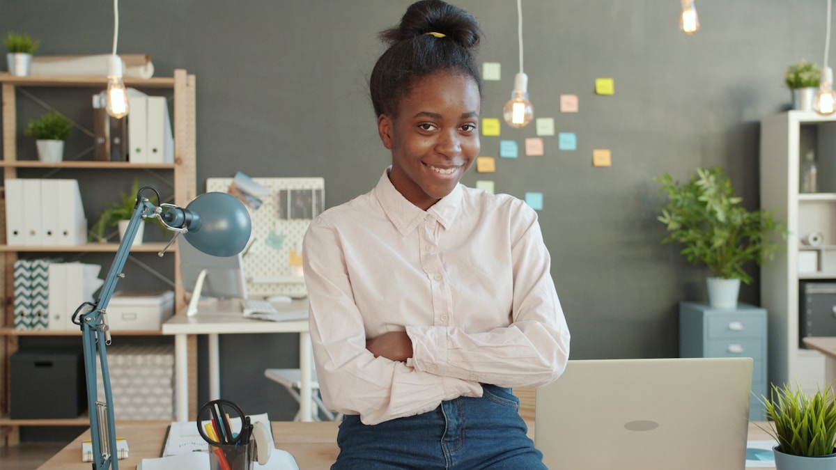 Young woman smiling with arms crossed in office