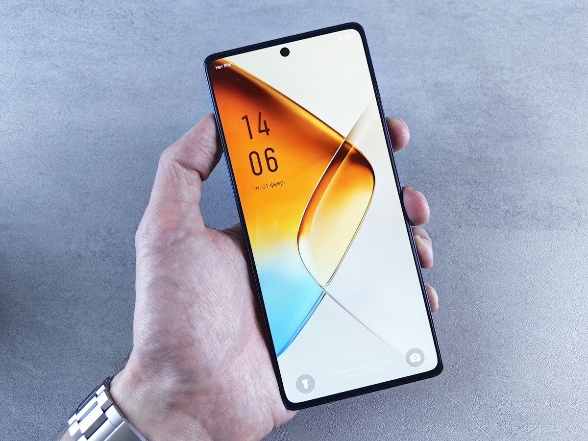 Hand holding modern smartphone with abstract wallpaper.