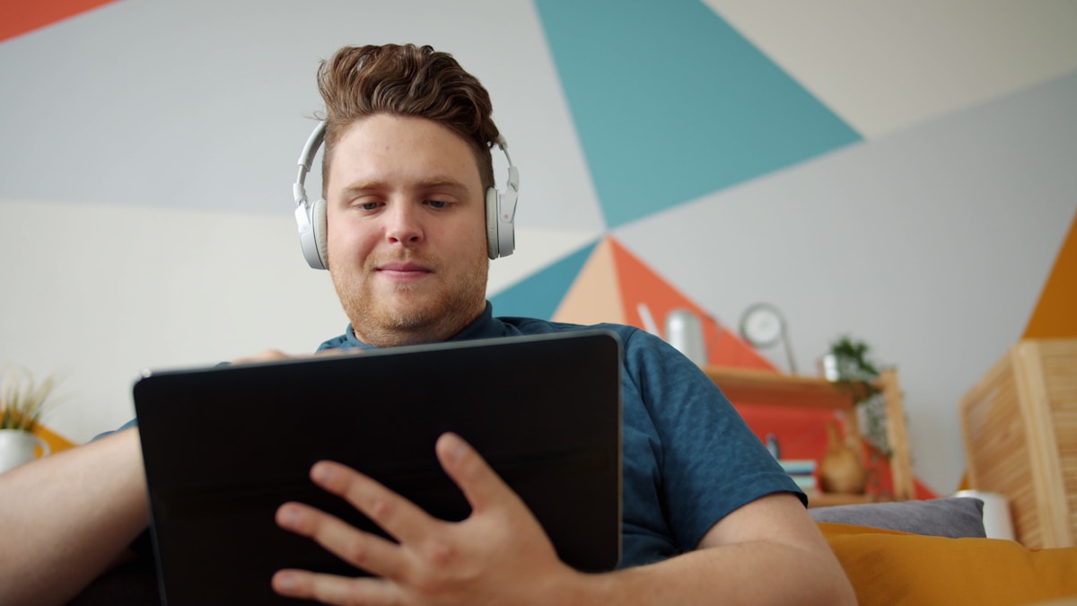 Homme concentré utilisant un ordinateur portable avec des écouteurs.