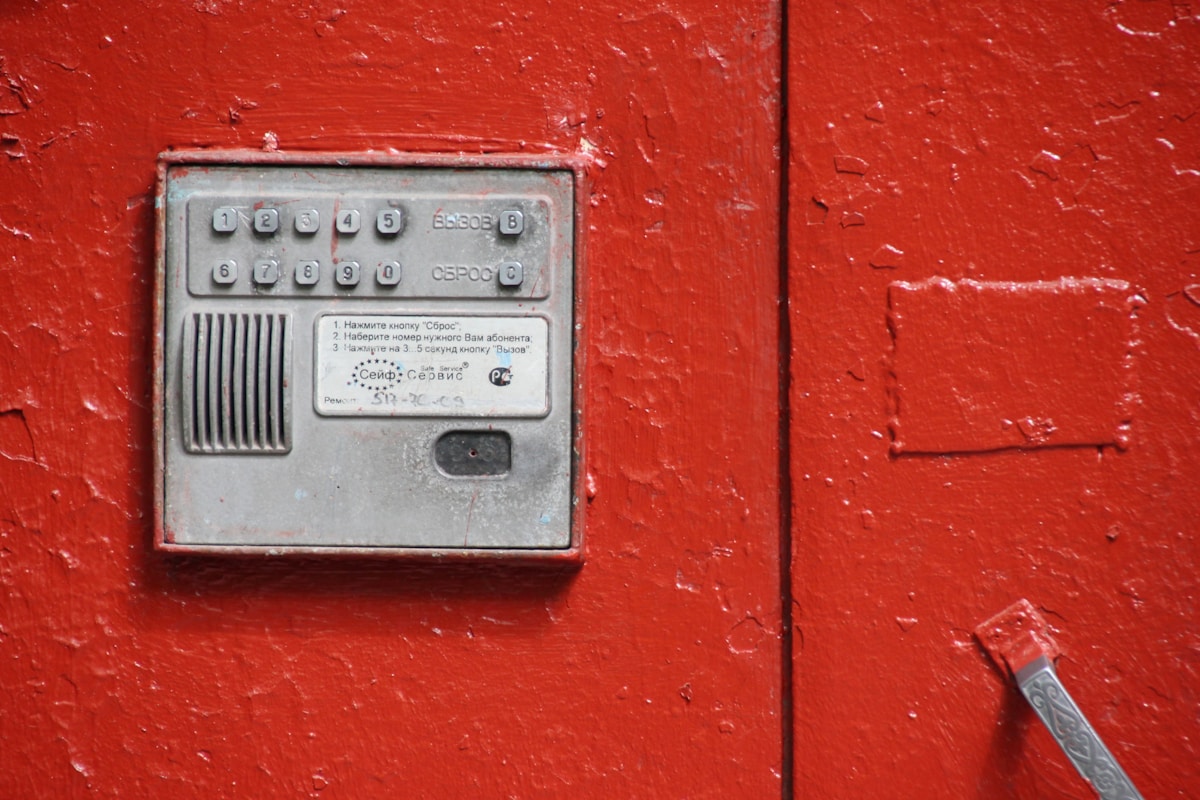 Boîte de commande électrique rouge sur un mur texturé.