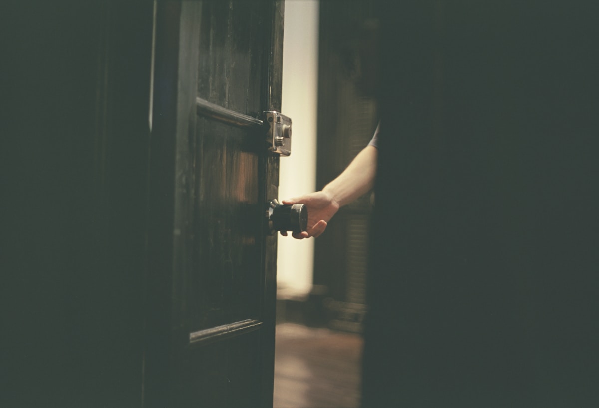Main ouvrant une porte sombre et mystérieuse.