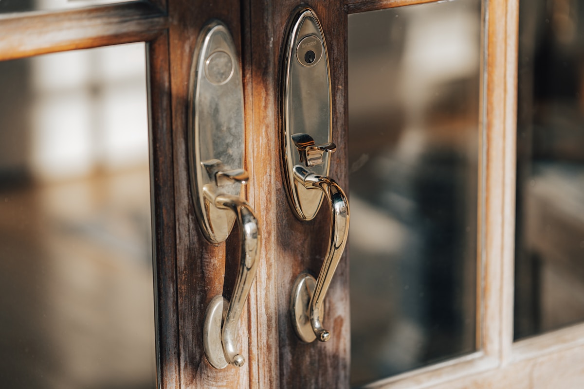 Poignées de porte en bois et en métal sur un cadre de fenêtre.