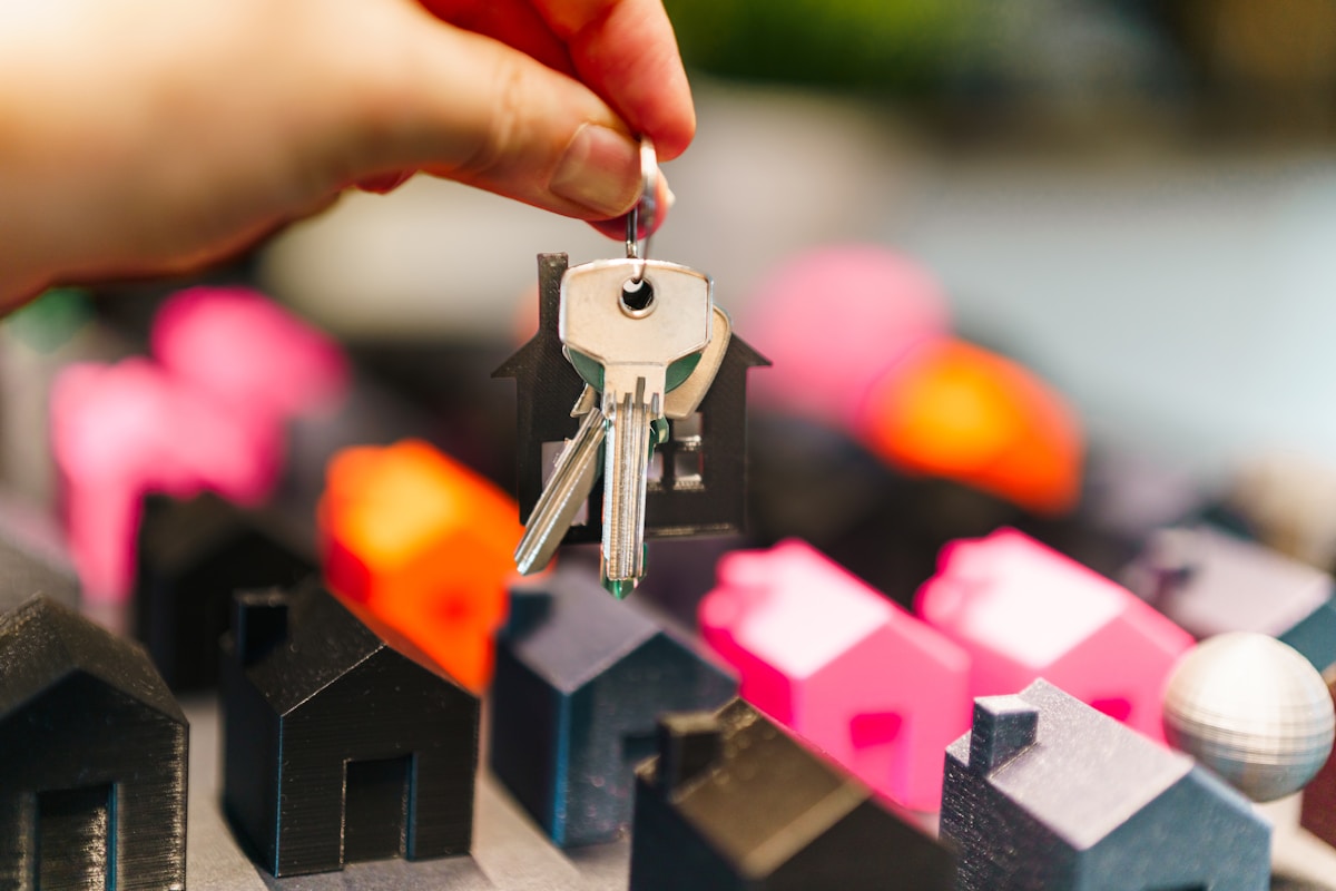 Clés de maison colorées sur un modèle de maison en bois.