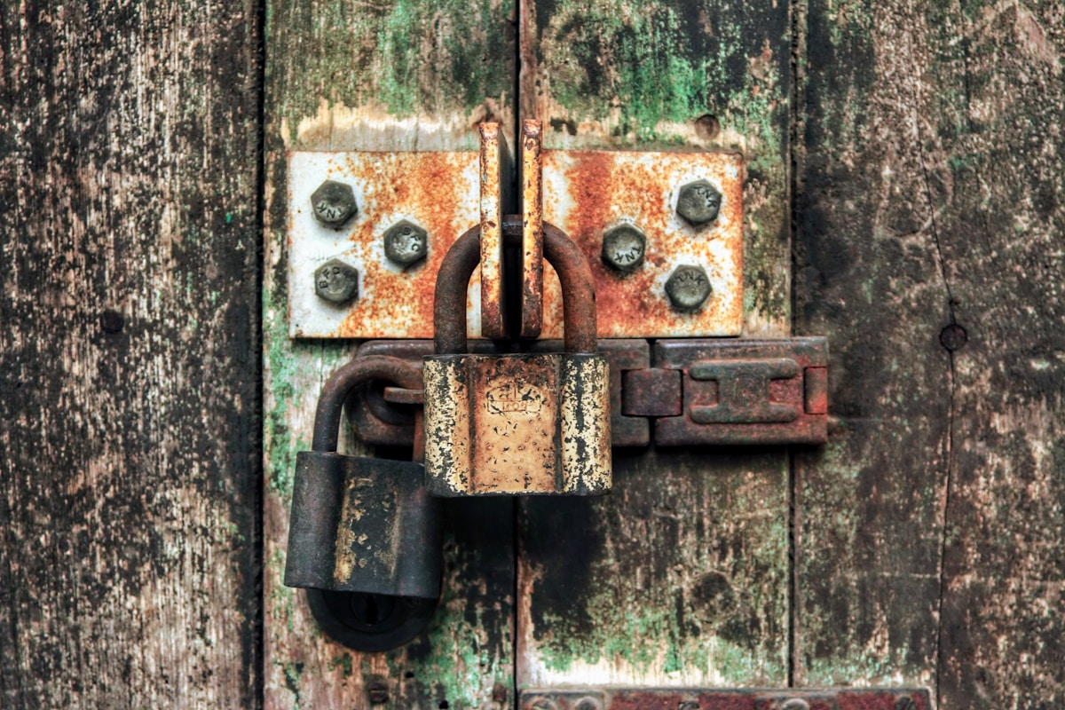 Vieux cadenas rouillé sur une porte en bois délabrée.