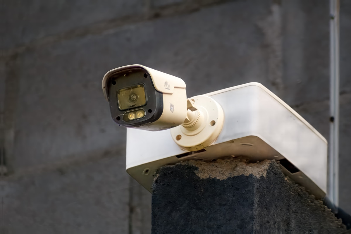 Caméra de surveillance extérieure montée sur un mur en béton.