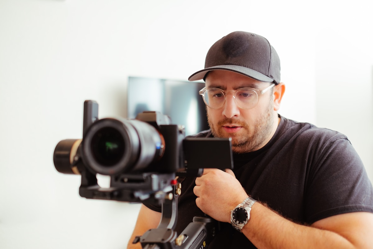 Homme barbu filmant avec une caméra professionnelle sur un stabilisateur.