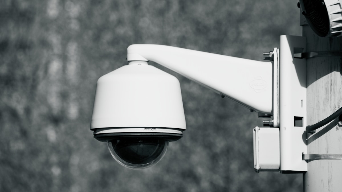 Caméra de surveillance blanche montée sur un mur.