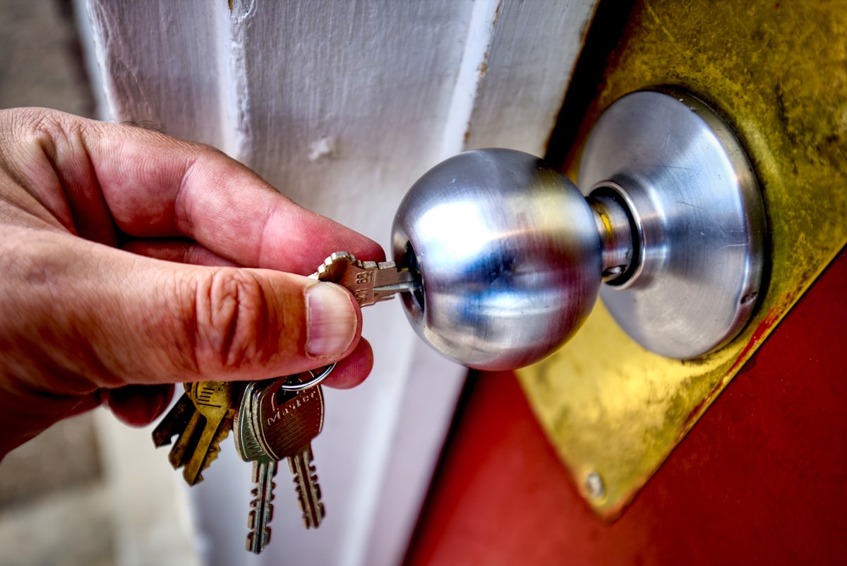 Clé de porte en métal insérée dans une poignée de porte.