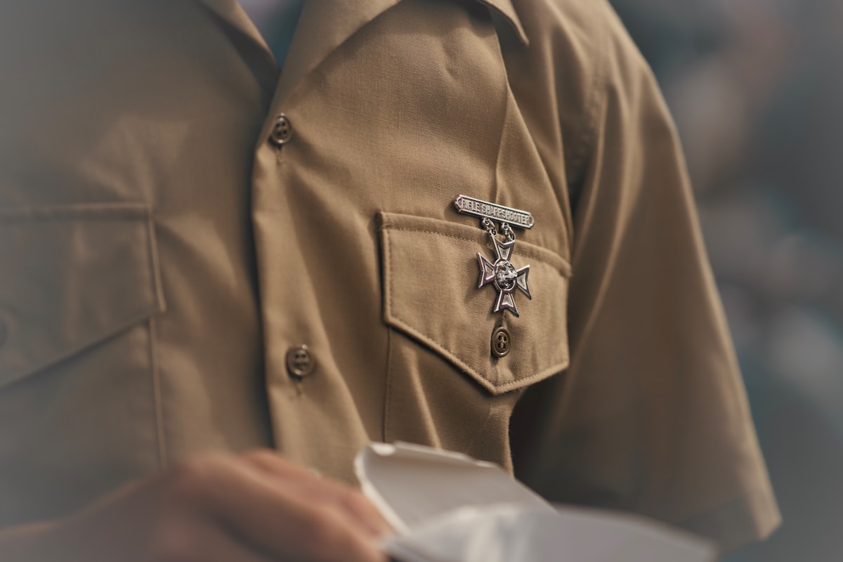 Veste beige avec une croix ornementale sur la poche.