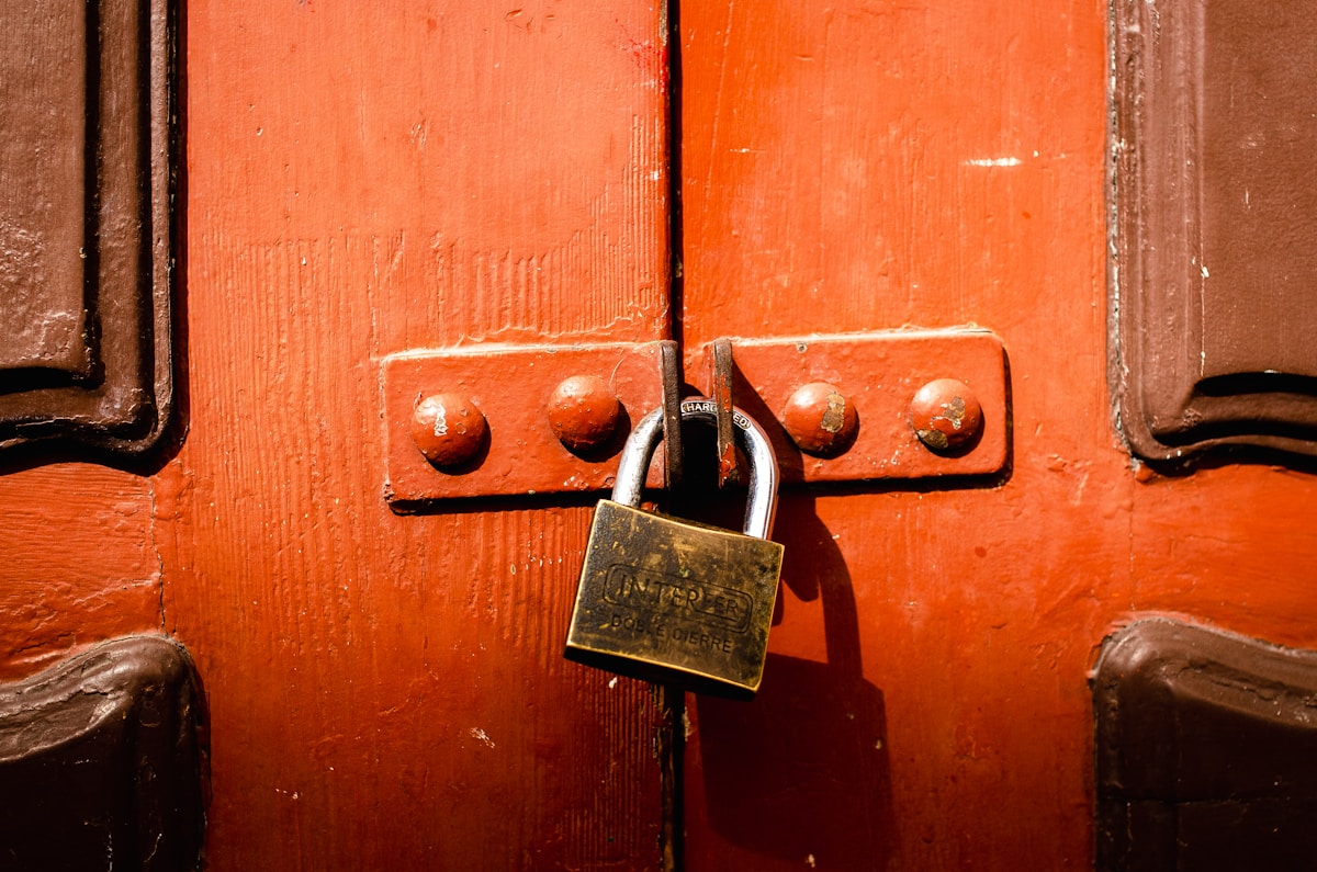 Porte en bois rouge avec cadenas doré verrouillé.