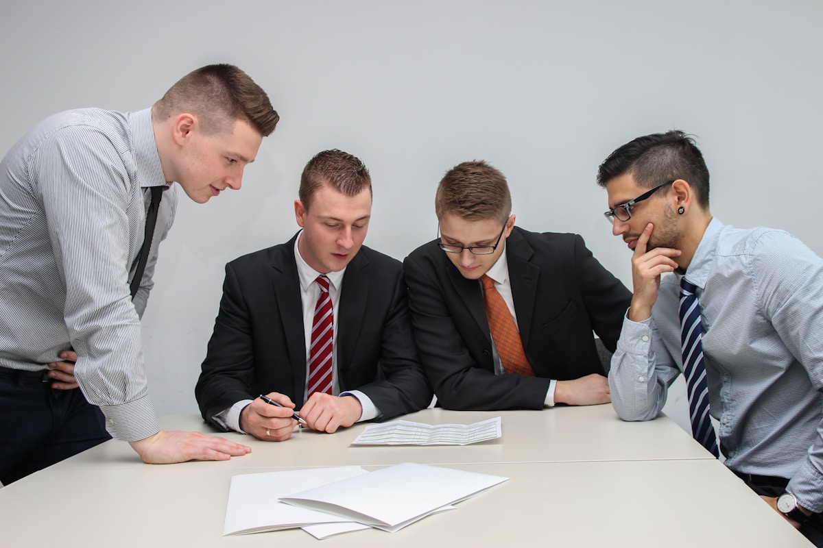 Quatre hommes d'affaires en costume discutent sérieusement autour d'une table.