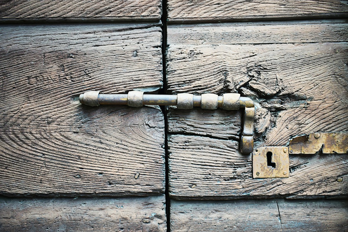 Loquet métallique rouillé sur ancienne porte en bois.